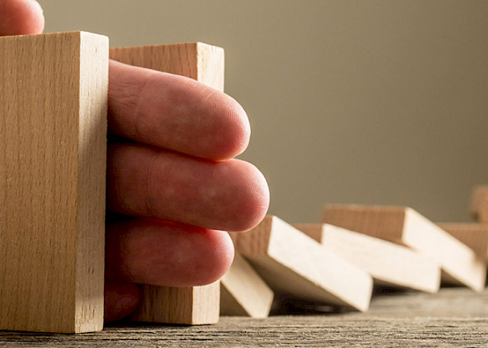 Hand die umfallende Dominosteine aufhält - © 