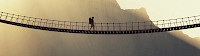 Mann mit Rucksack geht über eine Hängebrücke - © 